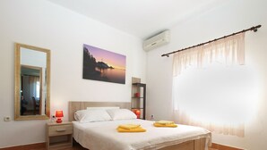 A bedroom with a bed, a bedside table, a mirror, a painting, an air conditioner, and a window with curtains. - Apartment 777/1814 (Istria - Fažana), 500m from the beach (Fažana)