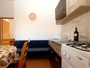A compact kitchen with a stove, sink, and a clock on the wall.