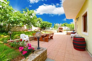 Eine Terrasse mit Tisch, Stühlen, einem Grill und einem Fass.