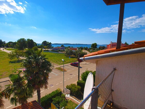 A view from a balcony overlooking a parking lot, a road, and a body of water.