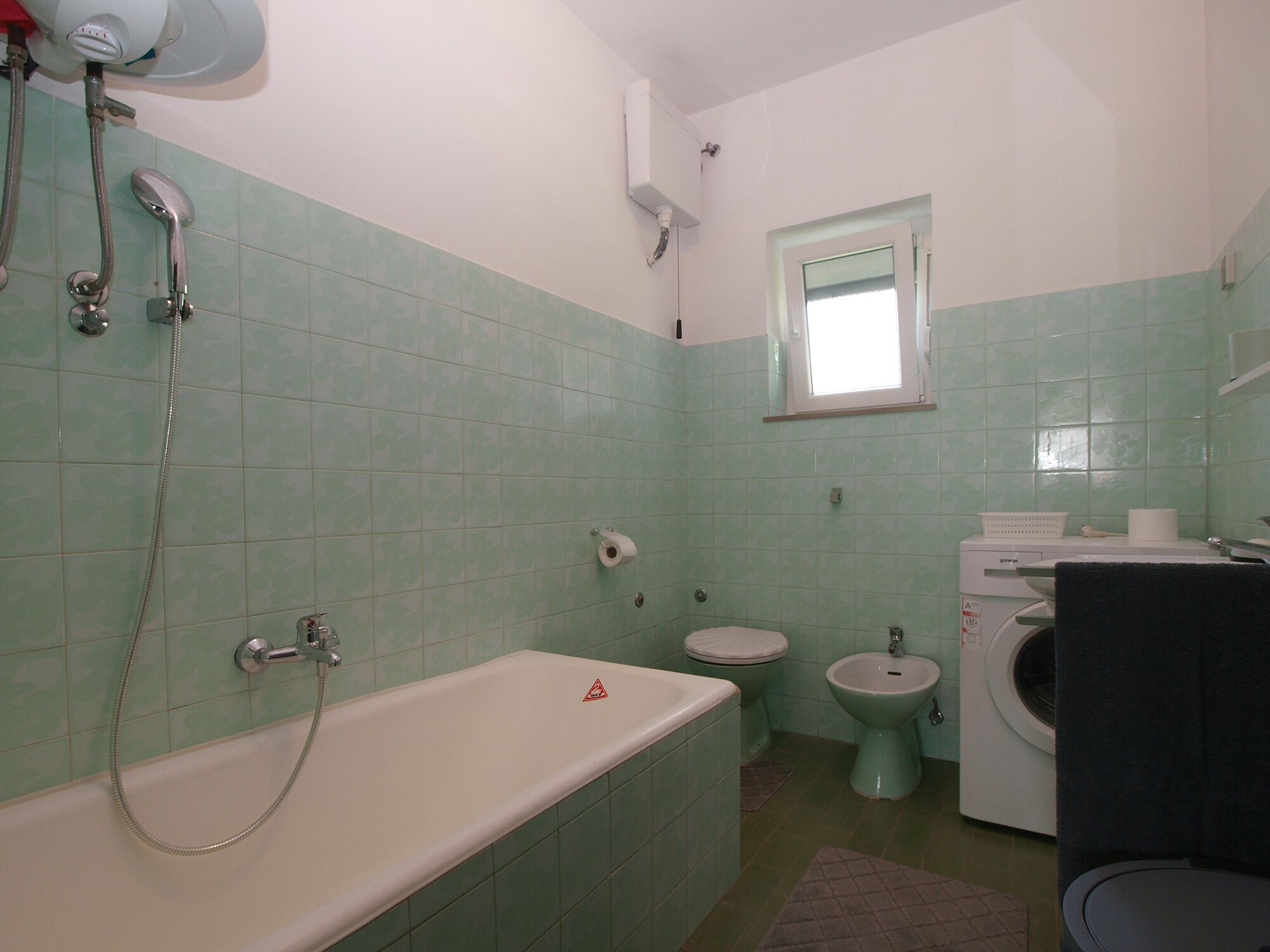 Ein Badezimmer mit Badewanne, Toilette, Bidet und Waschmaschine.