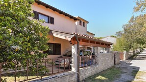 A two-story house with a covered patio and a stone wall. - Apartment 794/1844 (Istria - Pula), 1500m from the beach (Pula)