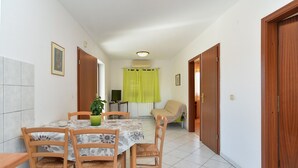 A dining area with a table, chairs, a potted plant, and a television in the background. - Apartment 794/1844 (Istria - Pula), 1500m from the beach (Pula)