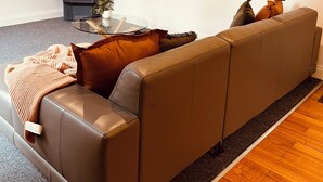A living room with a sofa, a glass coffee table, a fireplace, and a framed picture on the wall. - Manuka Retreat, Free unlimited WIFI.... (Halls Gap)