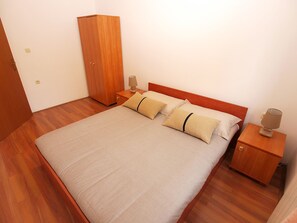 A neatly made bed with a wooden headboard, two bedside tables with lamps, and a wardrobe.