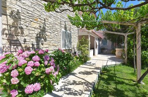 A stone building with a garden path leading to a covered area. - Apartment 810/1891 (Istria - Medulin), 600m from the beach (Medulin)