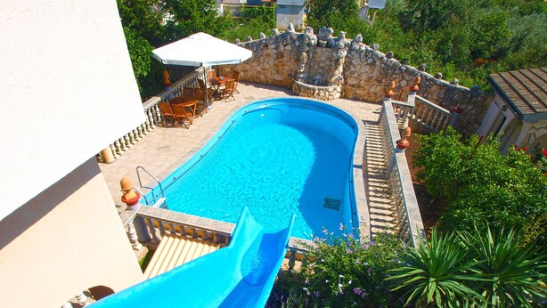 A swimming pool with a slide, surrounded by stone walls and greenery. - Apartment 811/1894 (Istria - Liznjan), 2500m from the beach (Liznjan)