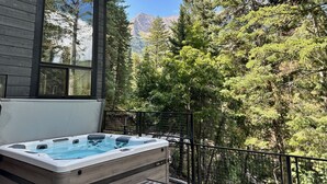 Un bain à remous sur une terrasse en bois avec vue sur les montagnes.