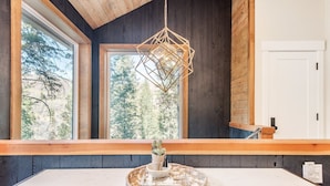 Une cuisine moderne dotée d’une grande fenêtre, d’un plafond en bois et d’un luminaire suspendu.