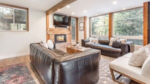 Un salon moderne doté d’une cheminée, de canapés en cuir et de grandes fenêtres offrant une vue sur l’extérieur.