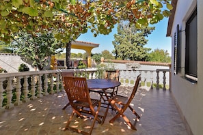 A patio with a round table and four wooden chairs, surrounded by a white balustrade.