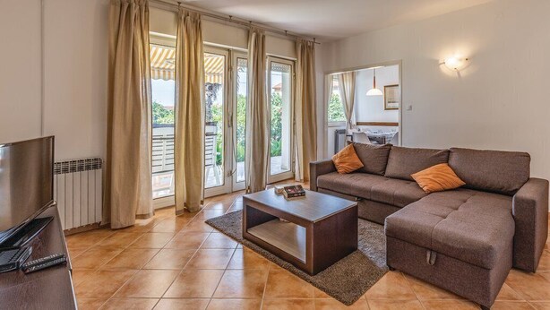 A living room with a sofa, coffee table, TV, and sliding glass doors to a balcony. - Apartment 812/1899 (Istria - Medulin), 300m from the beach (Medulin)