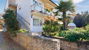 A two-story building with a balcony, a staircase, and a garden with various plants and a palm tree. - Apartment 812/1899 (Istria - Medulin), 300m from the beach (Medulin)