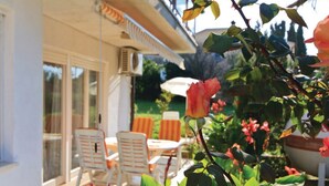 An outdoor patio area with a table and chairs, surrounded by greenery and a potted plant. - Apartment 812/1899 (Istria - Medulin), 300m from the beach (Medulin)