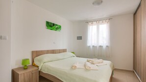 A neatly made bed with a green pillow, a bedside lamp, and a green rug on the floor. - Apartment 813/1900 (Istria - Medulin), 90m from the beach (Medulin)