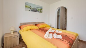 A neatly made bed with a yellow and orange bedspread, two pillows, and rolled towels on the bed. - Apartment 813/1901 (Istria - Medulin), 90m from the beach (Medulin)