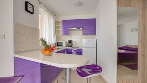 A modern kitchen with purple cabinets, a white countertop, and a fruit bowl. - Apartment 813/1902 (Istria - Medulin), 90m from the beach (Medulin)
