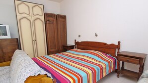 Une chambre à coucher comprenant un lit, une armoire en bois, des tables de chevet et un téléviseur.