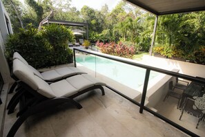 A balcony with a pool, lounge chairs, and a dining table with chairs. - Xaha Villas Suites & Golf Resort (Akumal)