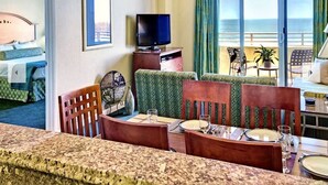 A hotel room with a balcony, a television, a dining area, and a bed. - Good Times and Tan Lines! (Daytona Beach)