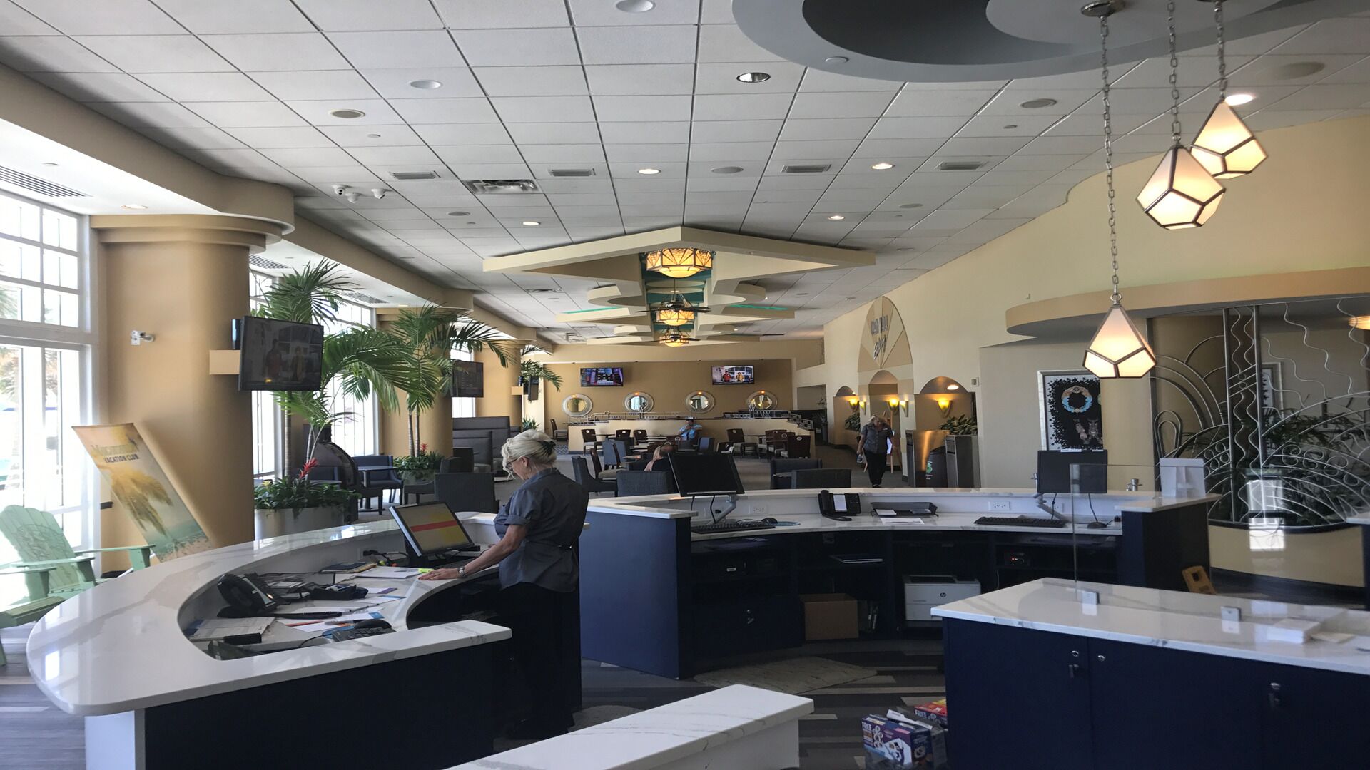 A spacious lobby with a curved reception desk, multiple seating areas, and a large chandelier.