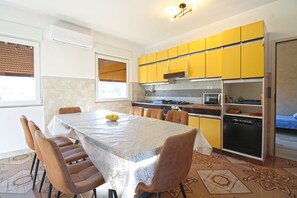 Une cuisine de taille réduite avec des meubles de couleur jaune, une table à manger avec des chaises et un four à micro-ondes.