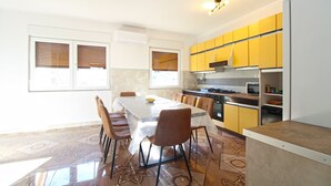 A modern kitchen with yellow cabinets, a dining table with chairs, and a tiled floor. - Apartment 826/1935 (Istria - Pula), 75m from the beach (Pula)