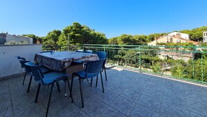 A terrace with a table and chairs, a green railing, and a view of buildings and trees. - Apartment 826/1935 (Istria - Pula), 75m from the beach (Pula)