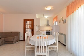 En kompakt opholdsstue med spiseplads, tekøkken og sofa.
