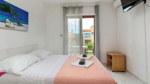 A hotel room with a bed, a painting, a TV, a window with curtains, and a wooden side table. - Studio apartment 828/1937 (Istria - Rabac), 700m from the beach (Rabac)