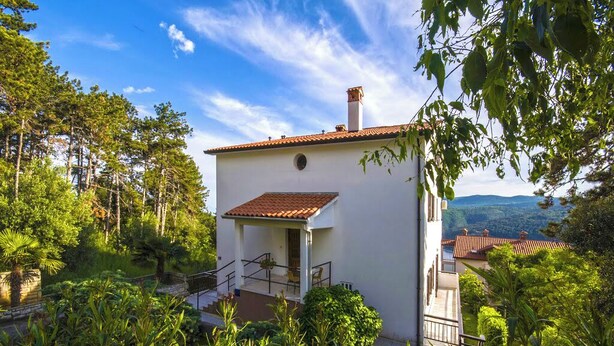 A small white building with a red-tiled roof, surrounded by lush greenery and trees. - Studio apartment 828/1937 (Istria - Rabac), 700m from the beach (Rabac)