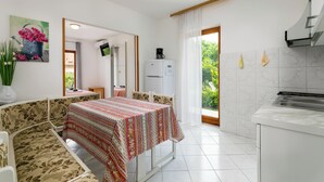 A compact room with a dining table, a sofa, a kitchen area, and a view of greenery outside. - Studio apartment 828/1937 (Istria - Rabac), 700m from the beach (Rabac)
