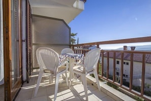 Enjoy a peaceful moment on this balcony with a table and chairs, taking in the view of the surrounding buildings.