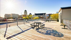 A wooden deck with tables and benches, overlooking a cityscape with historic buildings and a river. - Authentic loft for family of 4 in the heart of Old Quebec (La Cité-Limoilou)