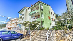 A multi-story building with balconies, a parking area, and a stone wall. - Apartment 832/1950 (Istria - Rabac), 700m from the beach (Rabac)