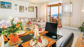 A dining area with a table set for four, a sofa, and a balcony with a view. - Apartment 832/1950 (Istria - Rabac), 700m from the beach (Rabac)
