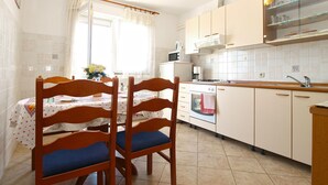 A kitchen with wooden cabinets, a dining table with chairs, and a window with curtains.