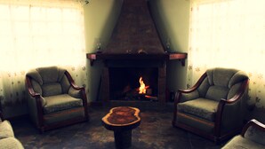 A room with two armchairs, a central coffee table, and a fireplace with a visible fire. - Finca El Yagual (Olmedo)