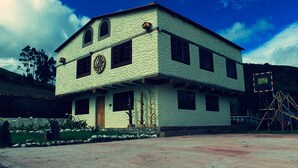 A two-story building with a textured facade, multiple windows, and a central door. - Finca El Yagual (Olmedo)