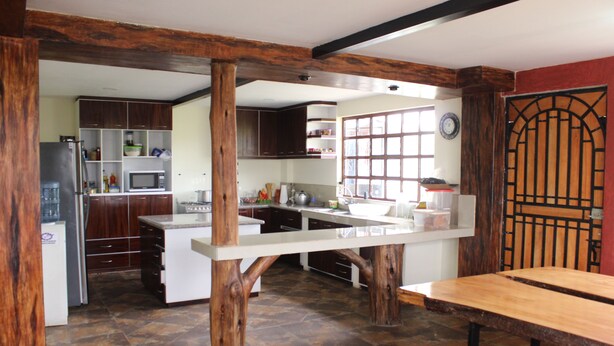 A kitchen with wooden beams, a central island, and a dining table. - Finca El Yagual (Olmedo)