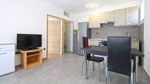 A modern kitchen with a built-in oven, a refrigerator, and a dining area with a table and chairs. - Apartment 847/2001 (Istria - Pula), 800m from the beach (Pula)