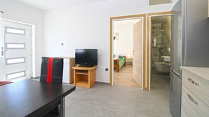 A room with a television on a stand, a dining table, a wardrobe, and a bathroom visible through an open door. - Apartment 847/2001 (Istria - Pula), 800m from the beach (Pula)