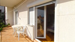A balcony with a table and chairs, a sliding glass door, and a view of the interior. - Apartment 847/2003 (Istria - Pula), 800m from the beach (Pula)