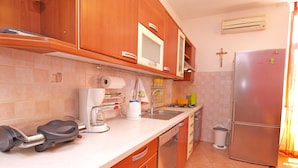 A compact kitchen with wooden cabinets, a stainless steel refrigerator, a coffee maker, and a sink. - Apartment 849/2007 (Istria - Fažana), 100m from the beach (Fažana)