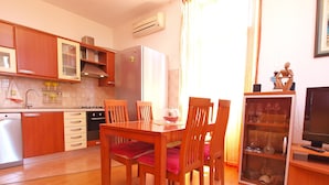 A compact kitchen with wooden cabinets, a built-in oven, and a dining area with a wooden table and chairs. - Apartment 849/2007 (Istria - Fažana), 100m from the beach (Fažana)