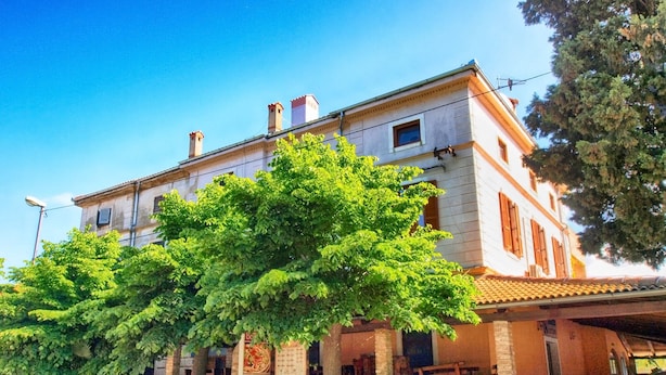 A two-story building with a covered porch and a large tree in front. - Apartment 849/2007 (Istria - Fažana), 100m from the beach (Fažana)