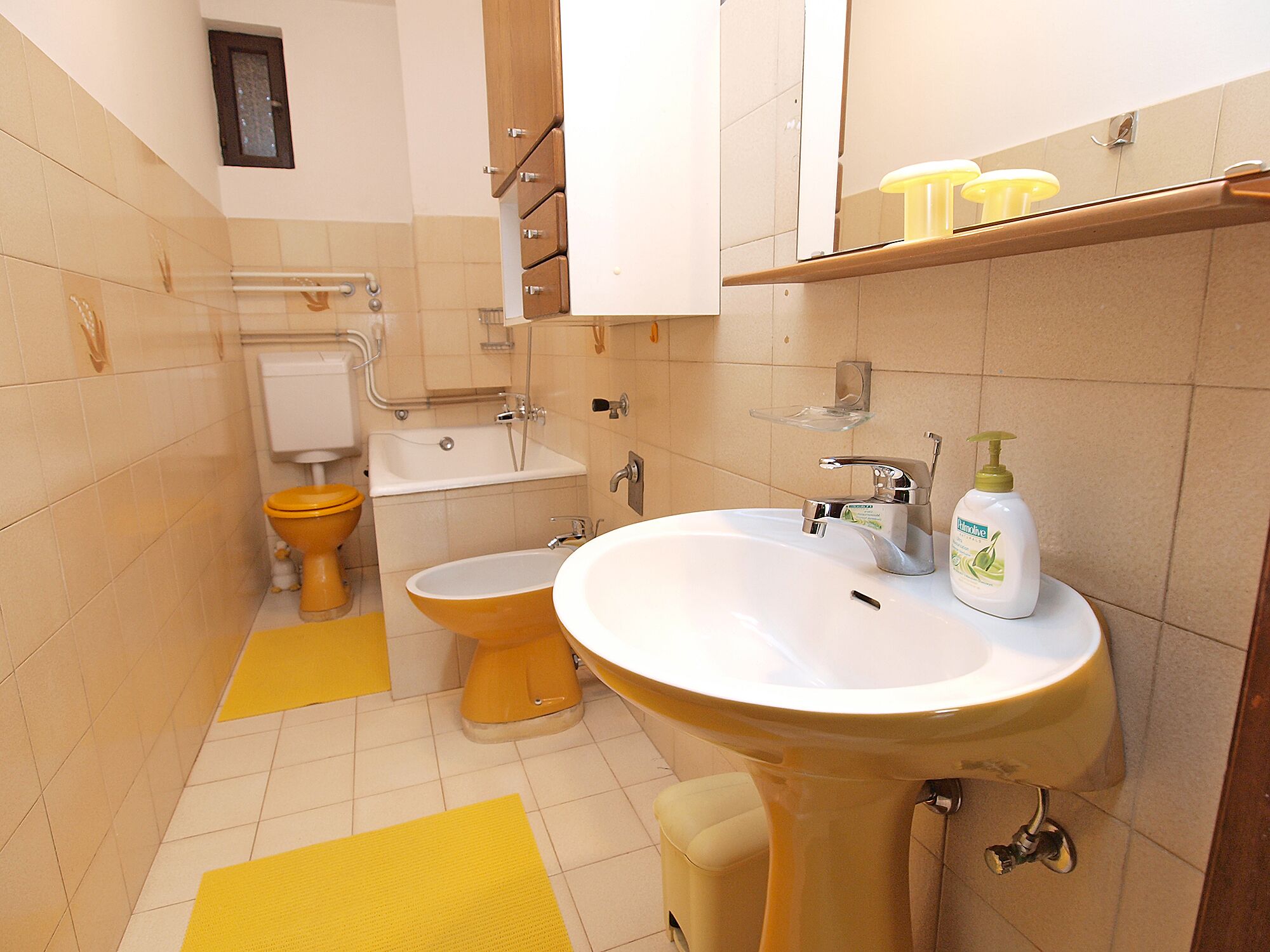 A bathroom with a yellow sink, a toilet, and a bathtub.