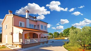 A two-story house with a balcony, a swimming pool, and a garden.