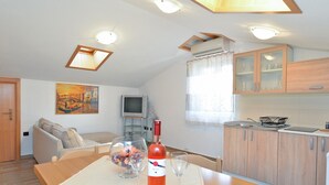 A cozy living room with a dining table set for two, a television, and a painting on the wall.