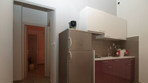 A compact kitchen with a stainless steel refrigerator, a sink, and a countertop.